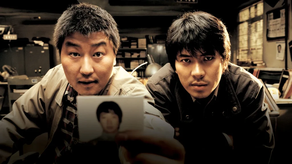 Poster film Korea Memories of Murder (2003) karya Bong Joon-ho, menampilkan dua detektif yang menyelidiki kasus pembunuhan berantai di pedesaan Korea.